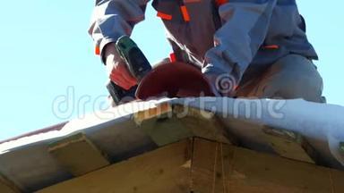 用电钻<strong>将</strong>红色金属瓷砖安装在木屋上，<strong>将</strong>穿工作服的人<strong>进行</strong>特写。 剪辑。 房屋建筑
